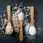 Different types of salt. Sea, himalayan and kitchen salt. Top view on three wooden spoons on black background